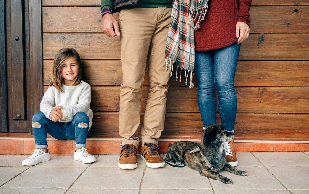 Smiling girl with parents and dog at wooden wall