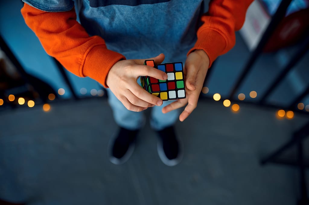 Male kid holds puzzle cube, focus on hand