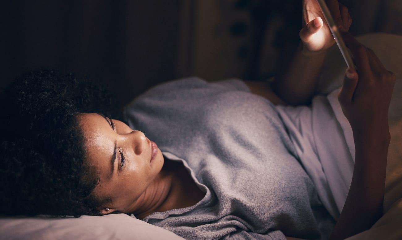 Light, night and phone with woman in bedroom for social media app, insomnia and networking. Communi